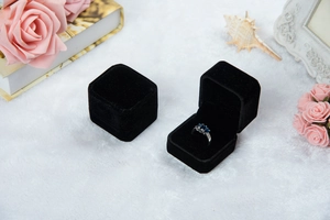 Elegante schwarze Samt-Schmuckschatulle mit blauem Diamantring, Rosen und Vintage-Deko