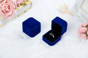 Detailansicht einer offenen blauen Samt-Ringschatulle mit Saphirring auf Plüsch