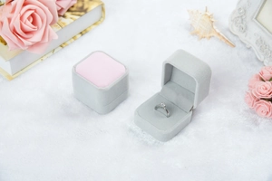 Elegante graue Samt-Ringbox mit rosa Polster in einer romantischen floralen Kulisse