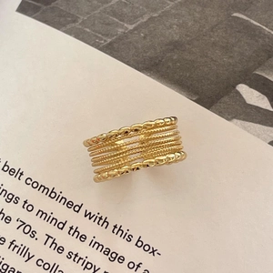 Detailed view of wide multi-layer gold ring with beaded texture on magazine background