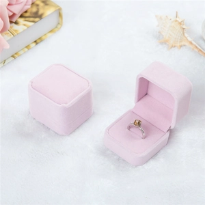 Pink velvet ring box with elegant flip lid shown open and closed on a white fur surface