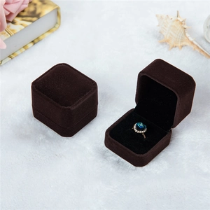 Brown velvet ring jewelry box in square shape shown with blue gemstone ring detail