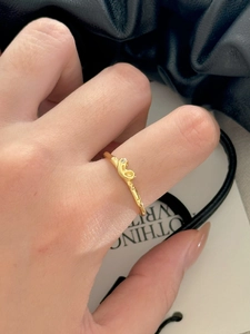 Macro detail of 18K gold-plated minimalist twisted ring with a tiny diamond setting