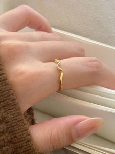 Detailed view of a wave-shaped gold ring featuring a minimalist curved design