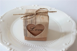 Detail of kraft paper favor box with heart cutout and rustic twine bow on ceramic plate