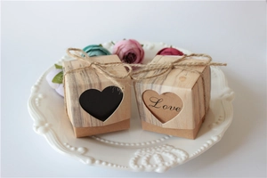 Detail of kraft paper favor boxes with heart cutout and twine bow on decorative plate