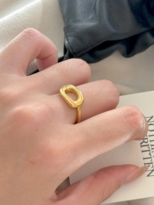 Close-up of a minimalist golden oval ring on a hand with sleek polished finish