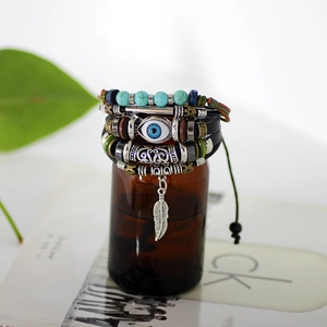 Multilayer leather braided bracelet with evil eye bead and feather charm on a bottle