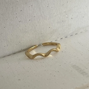 Close-up of polished gold wavy S925 sterling silver ring showing its curved profile