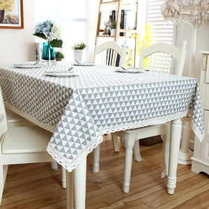 Detail of grey geometric triangle tablecloth with delicate white lace border on wood table