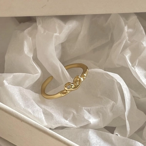 Detailed close-up of a golden irregular heart ring with a zircon stone in a jewelry box