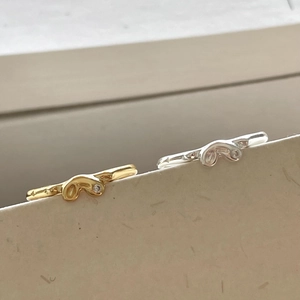 Detailed shot of gold and silver wavy abstract rings with a small inset zircon stone