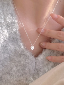 Close-up of minimalist 925 sterling silver heart necklace worn on a soft knit sweater