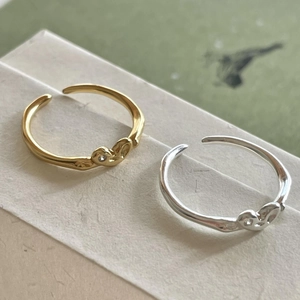 Detail of silver and gold heart shaped open rings with a small cubic zirconia accent