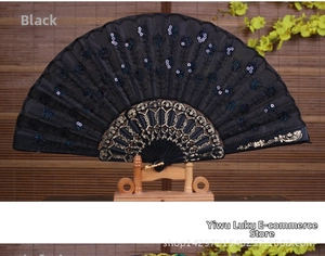 Detail of black sequined folding fan with golden hollow-out carvings on the frame and stand