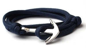 Macro detail of dark blue braided rope bracelet with silver anchor clasp on white background