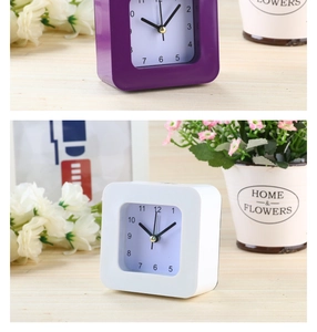 Detail of 3.5 inch square quartz alarm clock in purple and white on a wooden desk