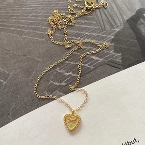 Detailed macro of golden heart pendant with embossed bow and vintage beaded edge design