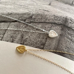 Detailed macro of heart pendants with bow accents on fine O-chains in gold and silver