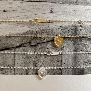 Close-up of heart-shaped relief pendant with S925 engraved clasp on delicate chain