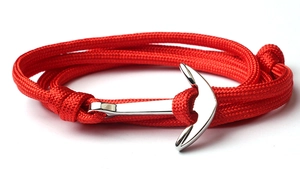 Detail of red woven nautical rope bracelet with silver anchor clasp on white background