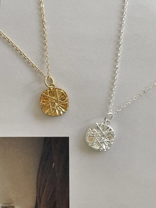 Detailed macro view of gold and silver round pendants with radial starburst engraving