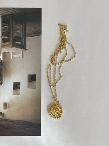 Macro shot of gold pendant with geometric radial texture on 925 sterling silver chain