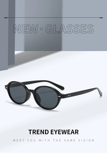 Detail view of oval Y2K sunglasses with black polished frames and dark gray lenses