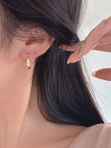 Gros plan détaillé de boucles d'oreilles goutte en or poli portées par un mannequin