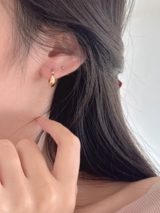 Détail de créoles et clous d'oreilles minimalistes en argent 925 plaqué or sur l'oreille