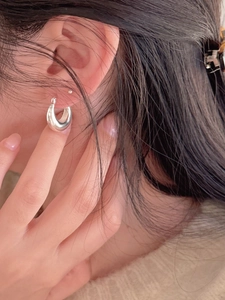 Gros plan d'une boucle d'oreille créole en argent sterling sur l'oreille du mannequin