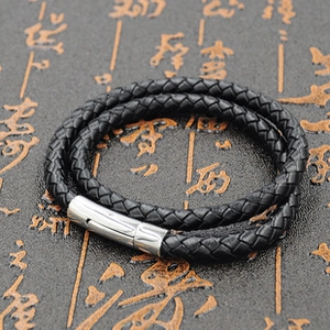 Detail of black double-layered braided leather bracelet with silver metal buckle clasp