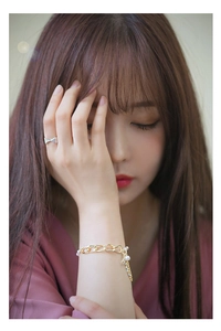 Detailed close-up of a silver bow ring and a gold pearl tassel bracelet on a model