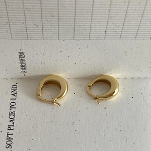 Vue détaillée de boucles d'oreilles créoles dorées polies sur un fond de papier décoratif