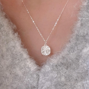 Minimalist 925 sterling silver necklace with geometric round pendant on a model wearing grey