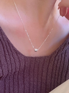 Detail of S925 sterling silver necklace with textured round bead pendant worn on neck