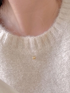Close-up of a minimalist S925 silver gold necklace with a textured bead pendant