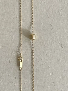 Macro shot of S925 sterling silver gold-plated necklace with a textured round bead