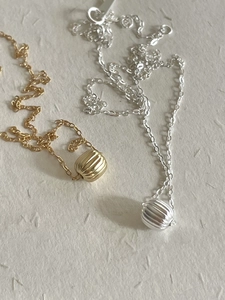 Detail view of gold and silver S925 sterling silver necklaces with textured bead pendants