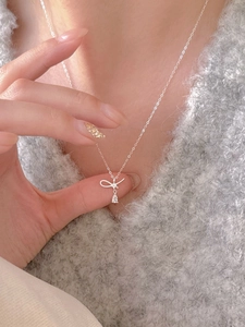 Gros plan du collier nœud argenté avec pendentif en zircon porté sur le cou d'un mannequin