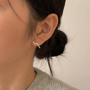 Detail view of a minimalist 925 silver bow stud earring worn on a model's ear