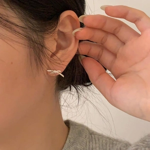 Close-up of minimalist 925 sterling silver bow knot earrings worn by a model