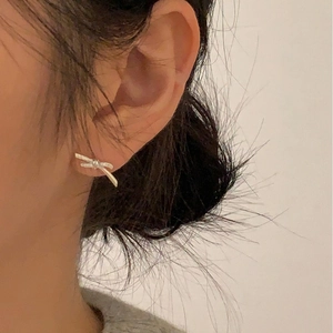 Close-up of minimalist 925 sterling silver bow knot stud earring worn by a model