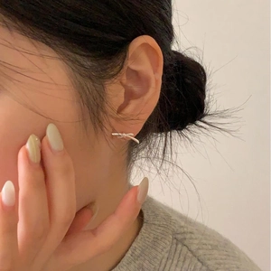 Close-up of minimalist silver bow earrings worn by a model in a cozy Korean style