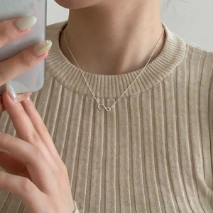 Close-up of a 925 sterling silver infinity pendant necklace worn on a woman neck
