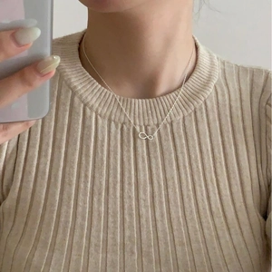 Close-up of S925 sterling silver infinity pendant necklace worn on a model neckline