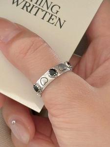 Detail view of 925 silver wide ring featuring alternating black heart stones and engravings