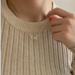 Minimalist 925 sterling silver infinity pendant necklace worn over a beige sweater