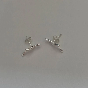 Macro shot of silver knot stud earrings in minimalist twisted metal design for women