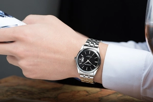 Business style silver metal watch with black dial and date display on a man's wrist